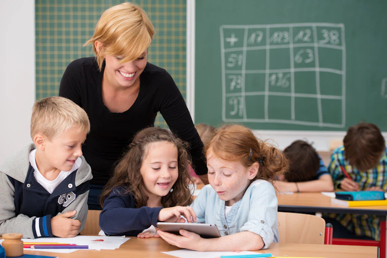 Teacher helping three primary students.