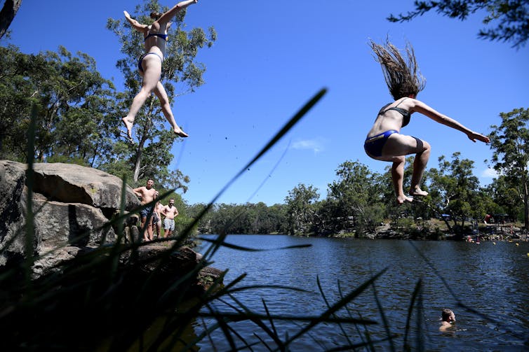 two women jump into waterway