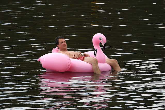 man floats on river in fink flamingo float