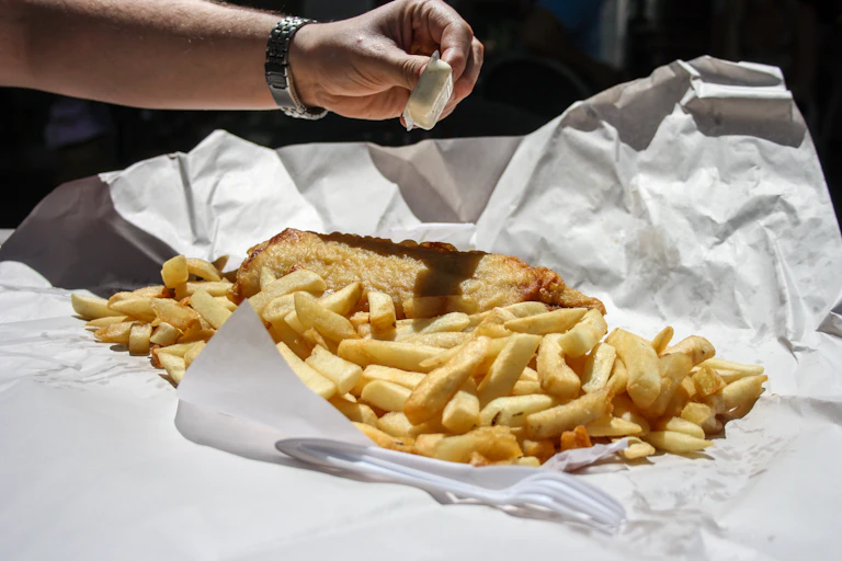A person squeezes lemon on fish and chips.