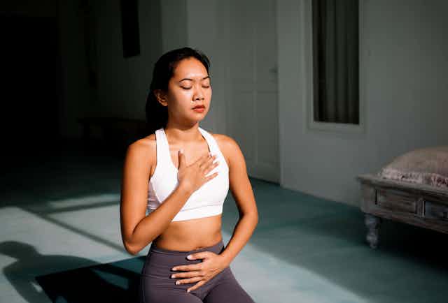 une jeune femme asiatique est en position de méditation/yoga