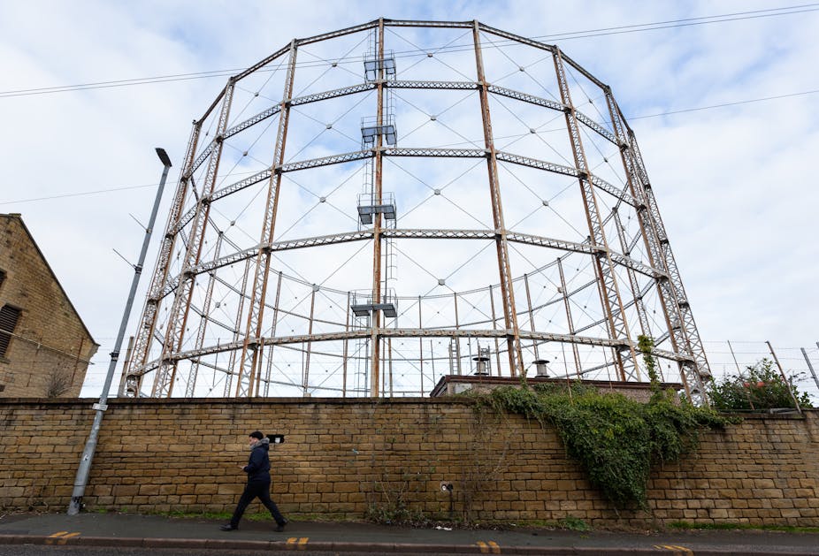 A person walks past a gas holder in Huddersfield, Britain, 26 January 2023. 