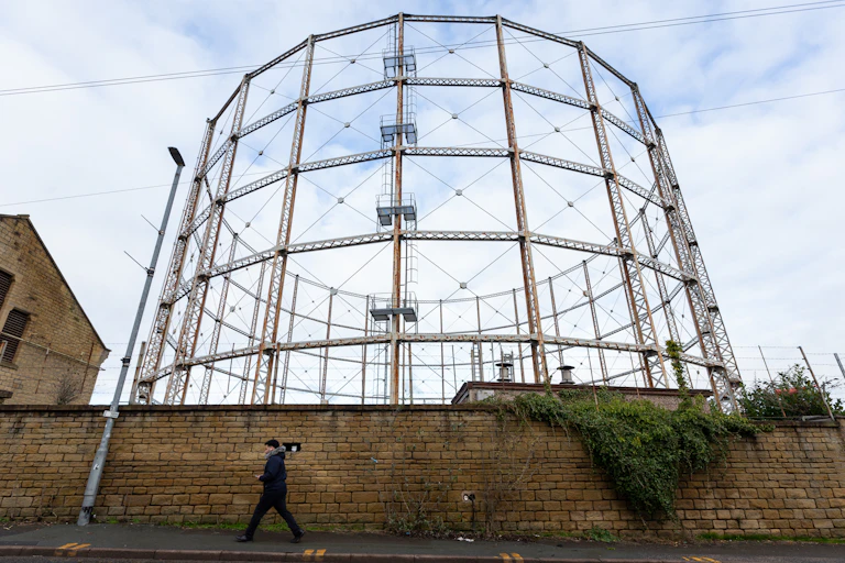 A person walks past a gas holder in Huddersfield, Britain, 26 January 2023.