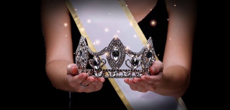 Prize Winning Award for Winner of Miss Beauty Queen Pageant Contest is Sash, Diamond Crown, studio lighting abstract dark draping textile background