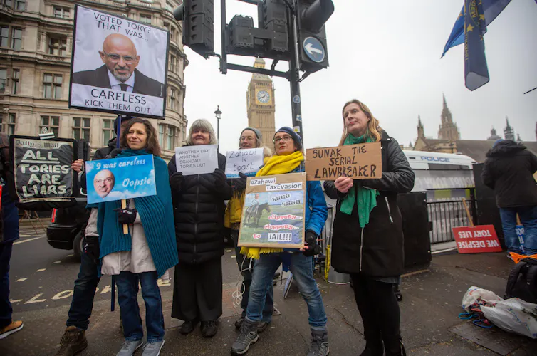 Protestors holding signs criticising Nadhim Zahawi over his tax dealings.