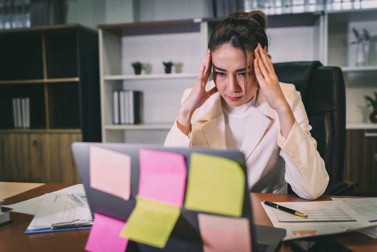 A woman takes her head into her hands in front of a computer