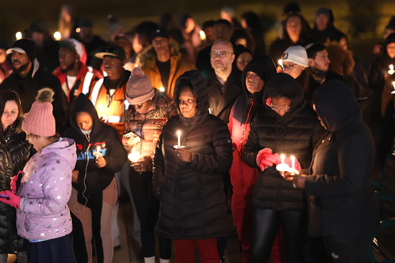A group of people are holding candlelights as they stand in the dark.