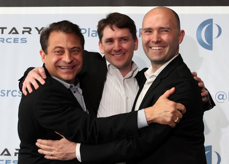 three men in suit jackets embrace