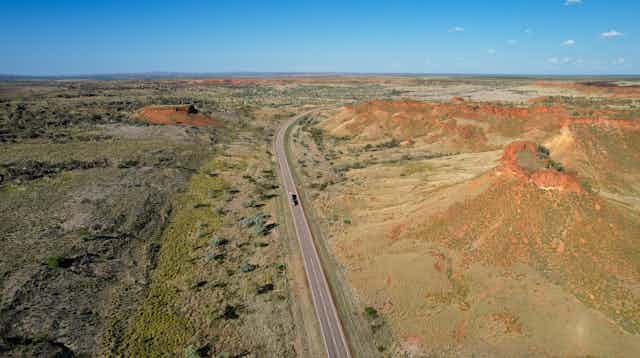 Aerial photo of the Great Northern Highway in Western Australia, among green and red hills.