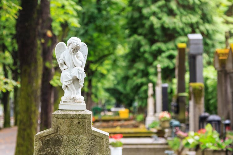 A stone angel sits atop a grave.