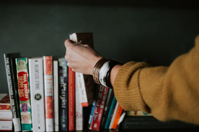 Hand picking a book off a bookshelf