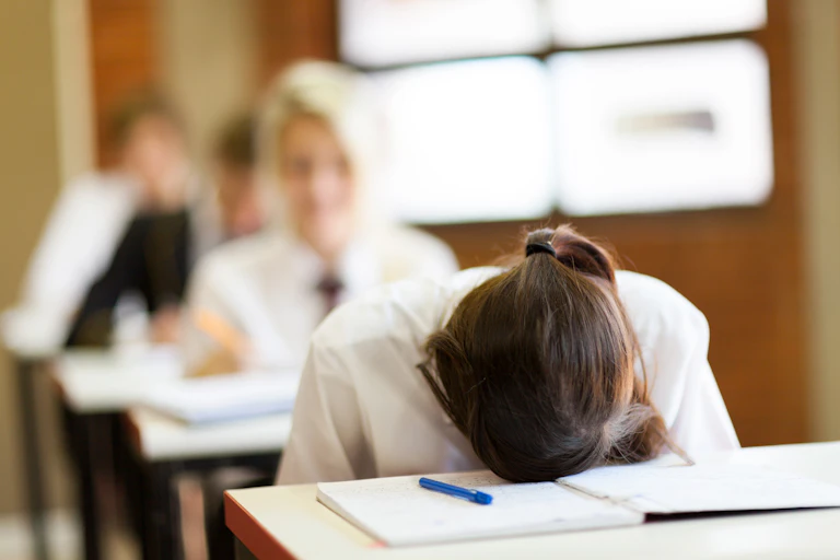 Student with their head on their desk.