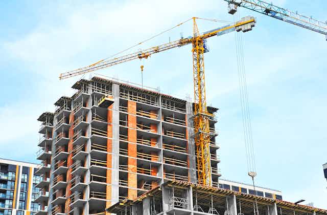 A construction crane is seen above a condominium that is under construction
