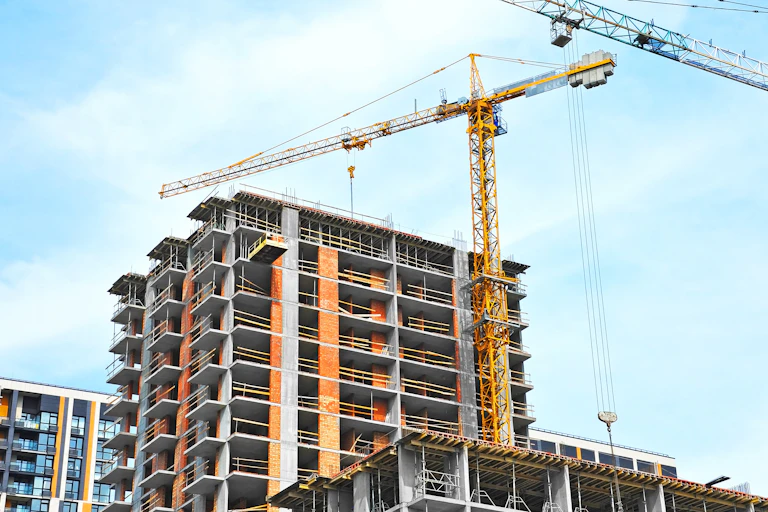 A construction crane is seen above a condominium that is under construction