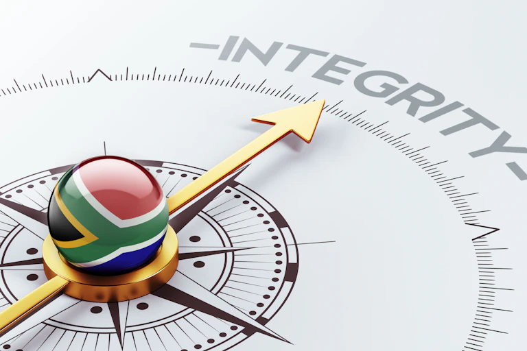 The gold needle of a compass points towards the word "integrity". A marble decorated with the South African flag sits in the centre of the compass