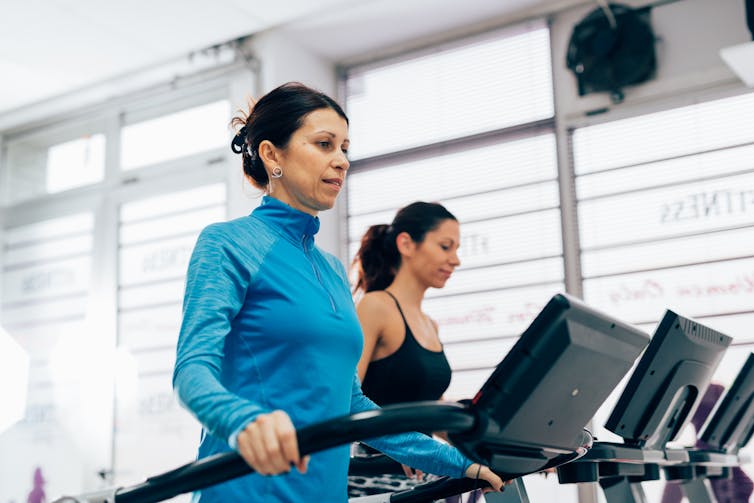 Two women at the gym using the treadmill.