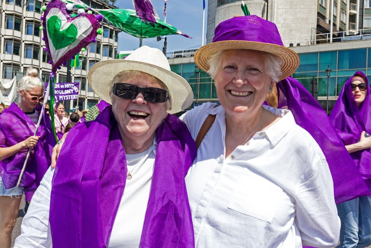 Two women dressed in purple and white.