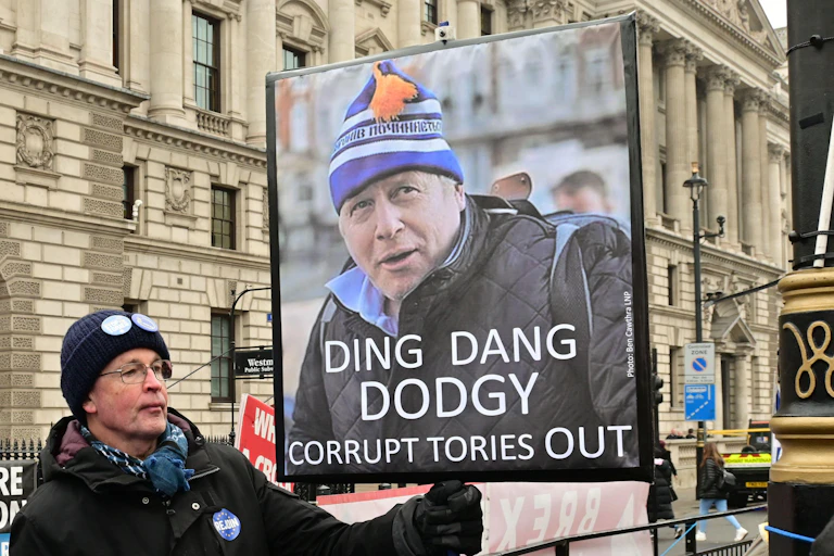 A protester holding a sign reading "ding dang dodgy. Corrupt tories out'