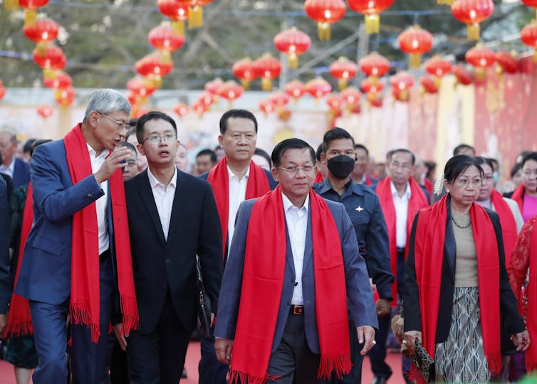 A group of Burmese men and women, some wearing red scarves to denote their allegiance to the military junta.