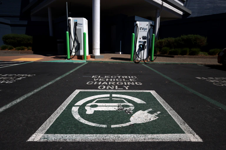 Parking spots with EV chargers and 'Electric Vehicle Charging Only' stenciled on the pavement.