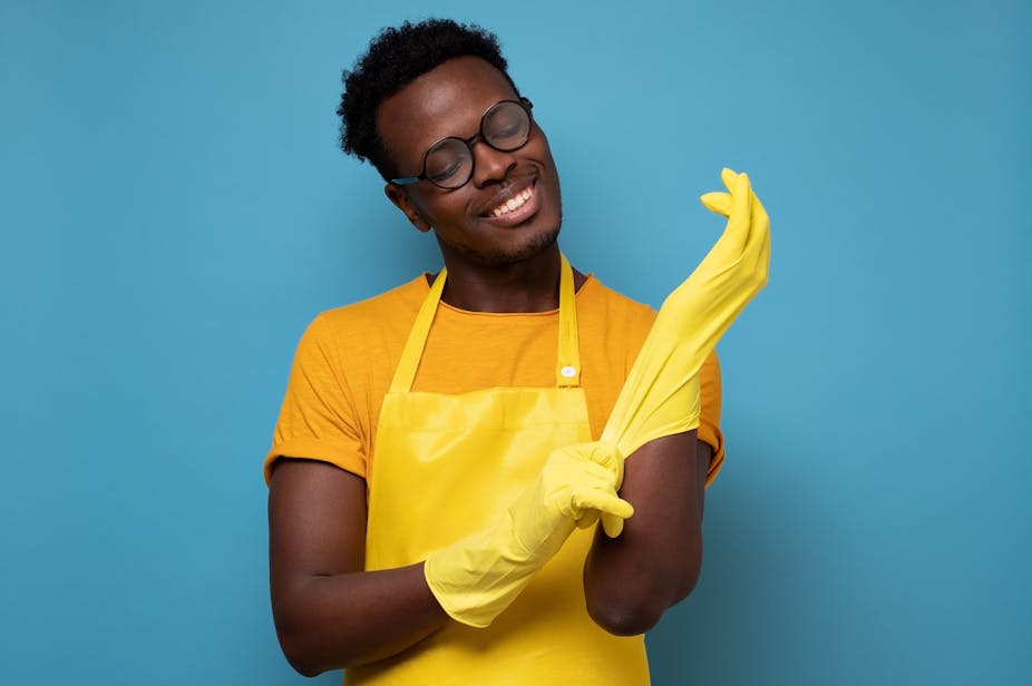 man in glasses putting on yellow rubber gloves for cleaning