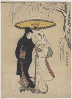 Two lovers walk beneath a parasol in the snow. He wears all black and she all white.