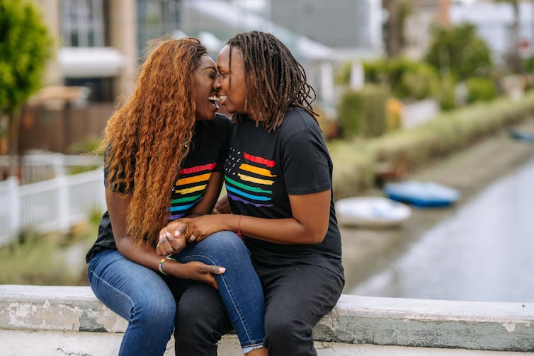 Two black women kissing.