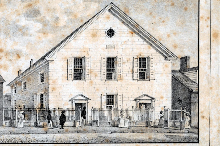 An old black and white drawing of a church with a sloping, corrugated roof and people men and women walking in front.