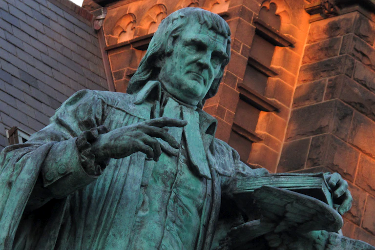 A green statue of John Witherspoon at Princeton University overlooks a common area.