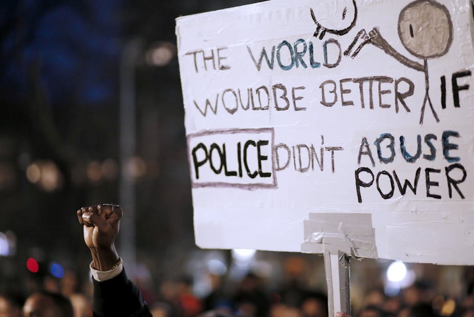A raised fist next to a sign that says 'The world would be better if police didn't abuse power'