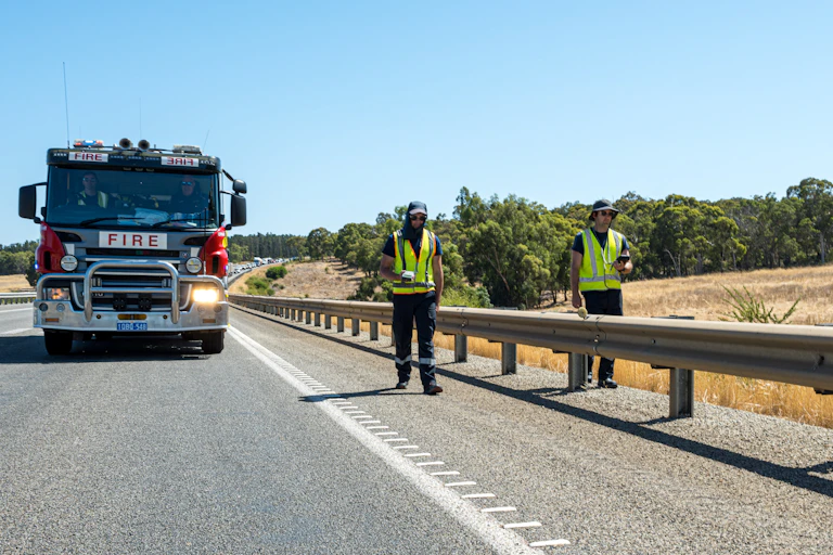 fire truck follows two men walking along road