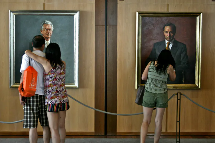 people looking at portraits of Bob Hawke and Paul Keating