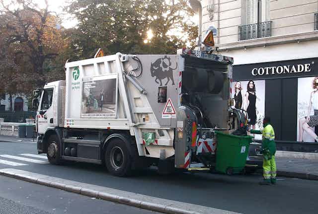 Éboueur à Paris derrière un camion-poubelle