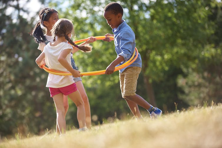 Three children playing with hula hoops.