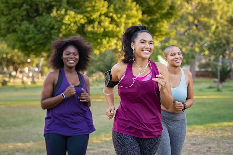 Three women smiling while running