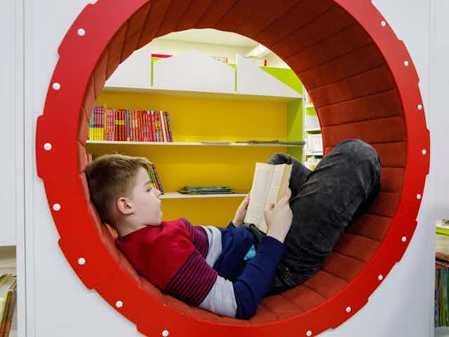 Un jeune garçon lit un livre assis dans un cercle rouge.