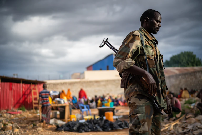 Soldat armé en treillis dans un camp de réfugiés