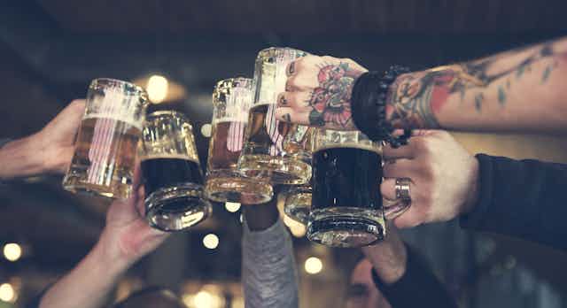 Friends raise pint glasses to cheers. 
