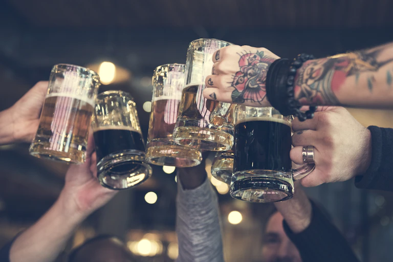 Friends raise pint glasses to cheers.