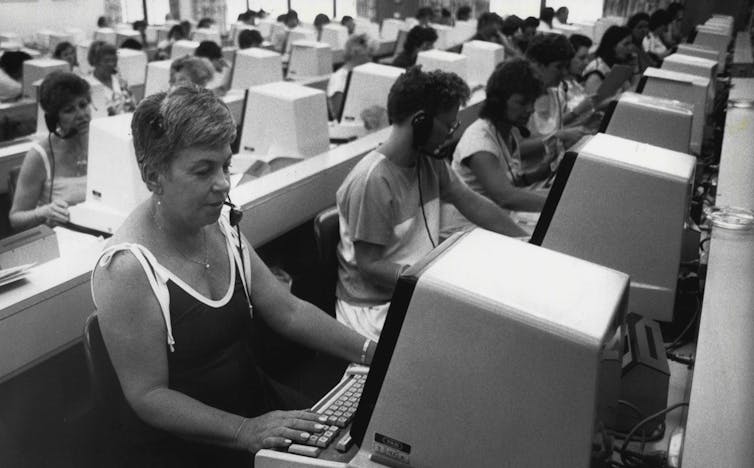 Black and white photo of rows of women sitting at computer terminals.