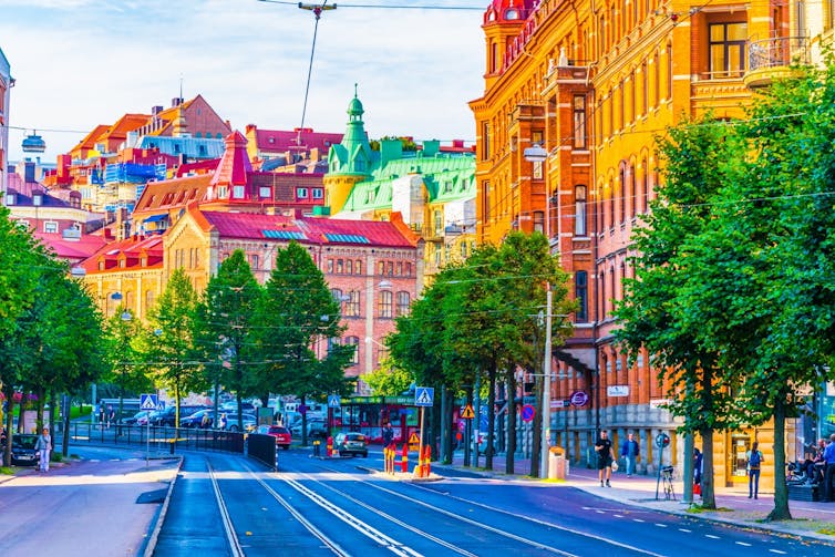 A street view of Gothenburg with trees lining the road and colourful buildings in the background.