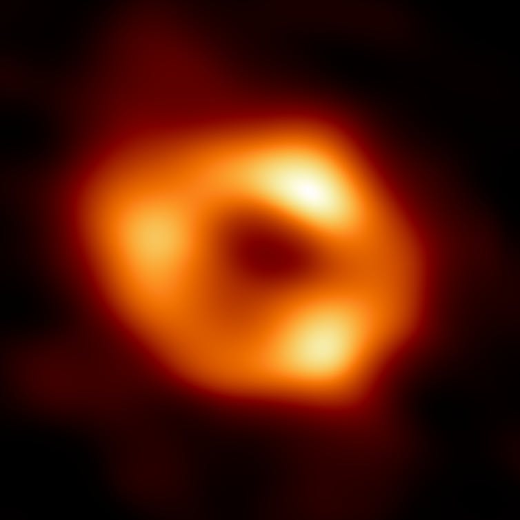 A blobby photo of a red-yellow ring around a central black hole.