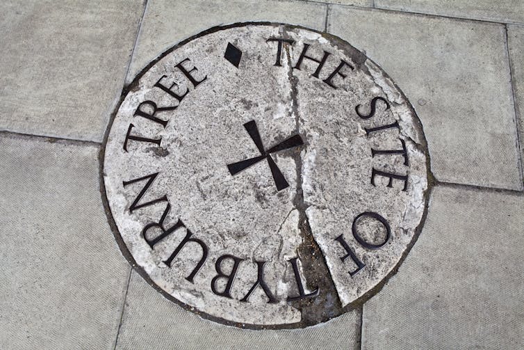 An overhead shot of a metal plaque with an inscription amid paving stones.