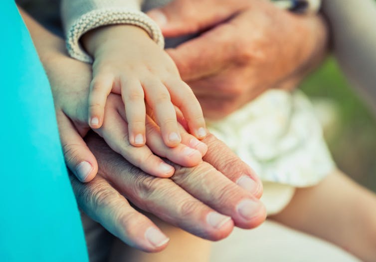 Baby girl, child and senior man comparing the hands size. Two different generations concept.