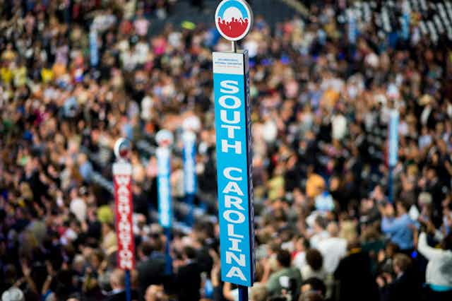 The sign for the South Carolina delegation at the Democratic National Convention stands above a convention hall crowded with people.