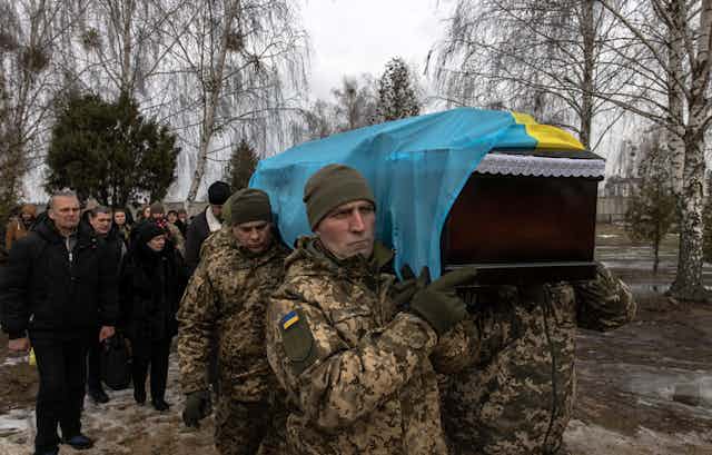 Ukrainian soldiers carry a comrade's coffinat a funeral in Bucha, northwest of Kyiv, Ukraine, 23 December 2022.