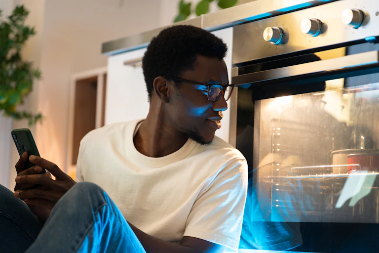 Man sat on floor by oven as cake cooks