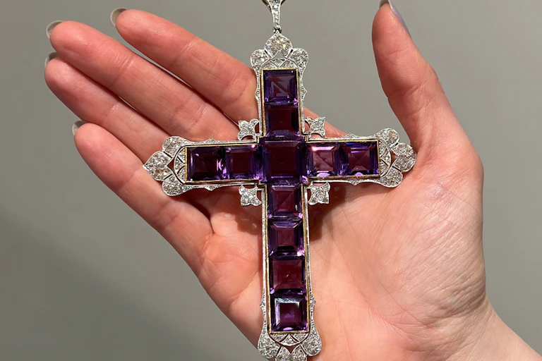 A large palm-sized cross made of purple square jewels and encrusted around the edges with diamonds.