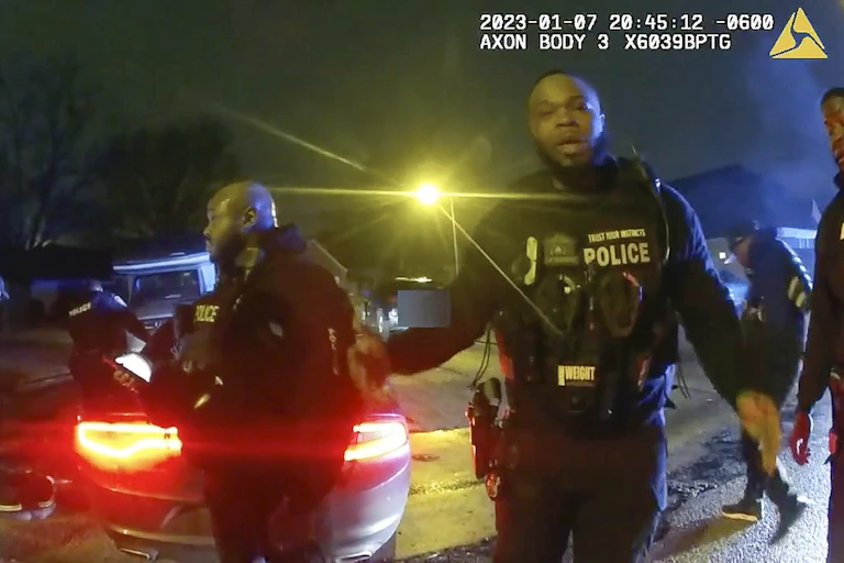 Police officers in uniform are captured on an video image in front of a car.