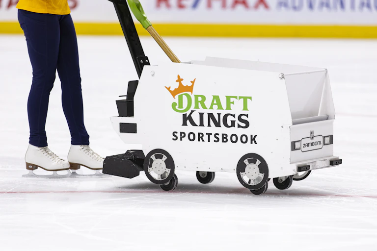 Woman wearing ice skates pushing a mini zamboni.